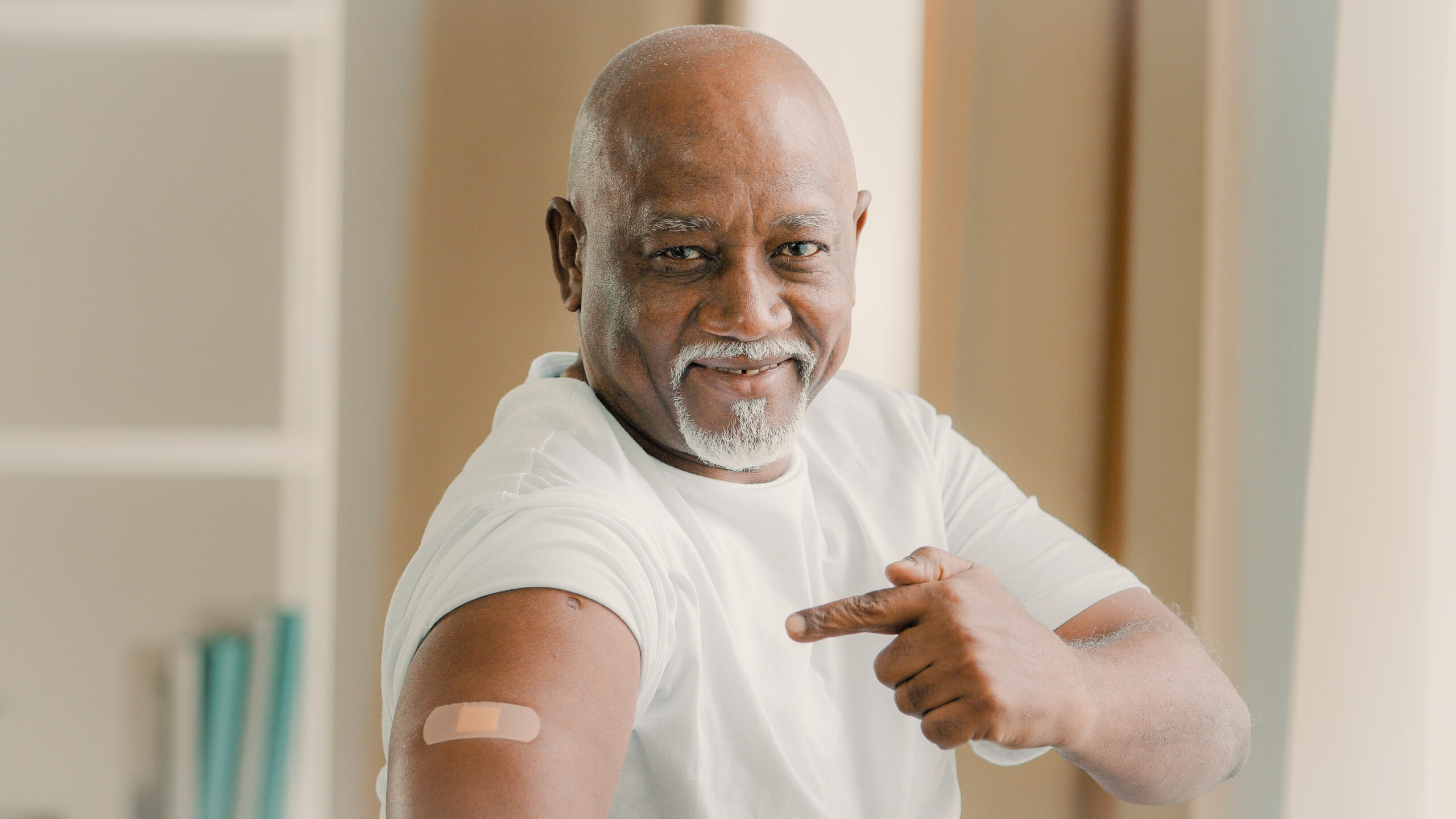 Portrait african american old senior mature man patient shows medical plaster on shoulder demonstrates injection mark satisfied male client after vaccination with covid-19 virus vaccine antivirus dose