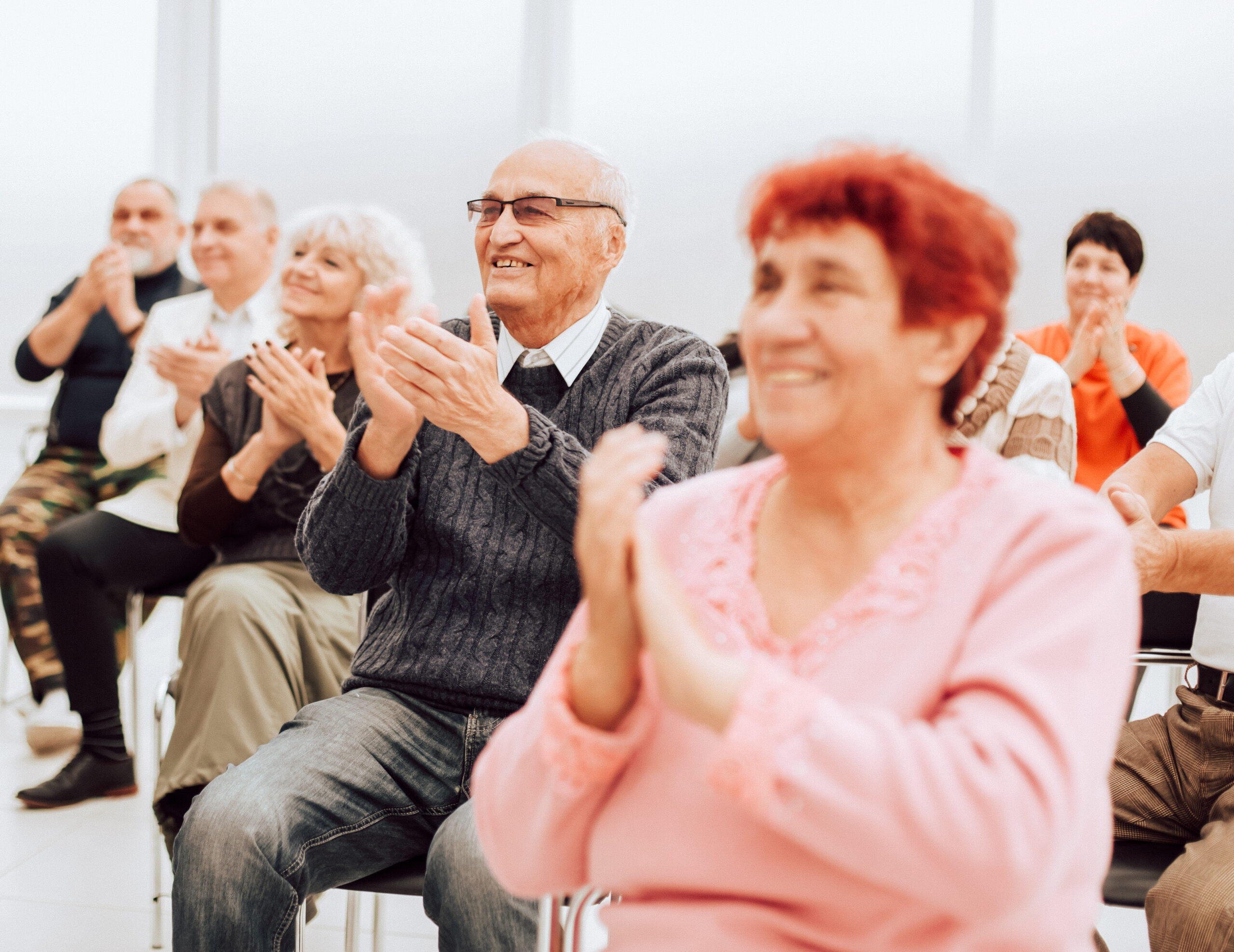 A group of senior citizens applaud in the conference room