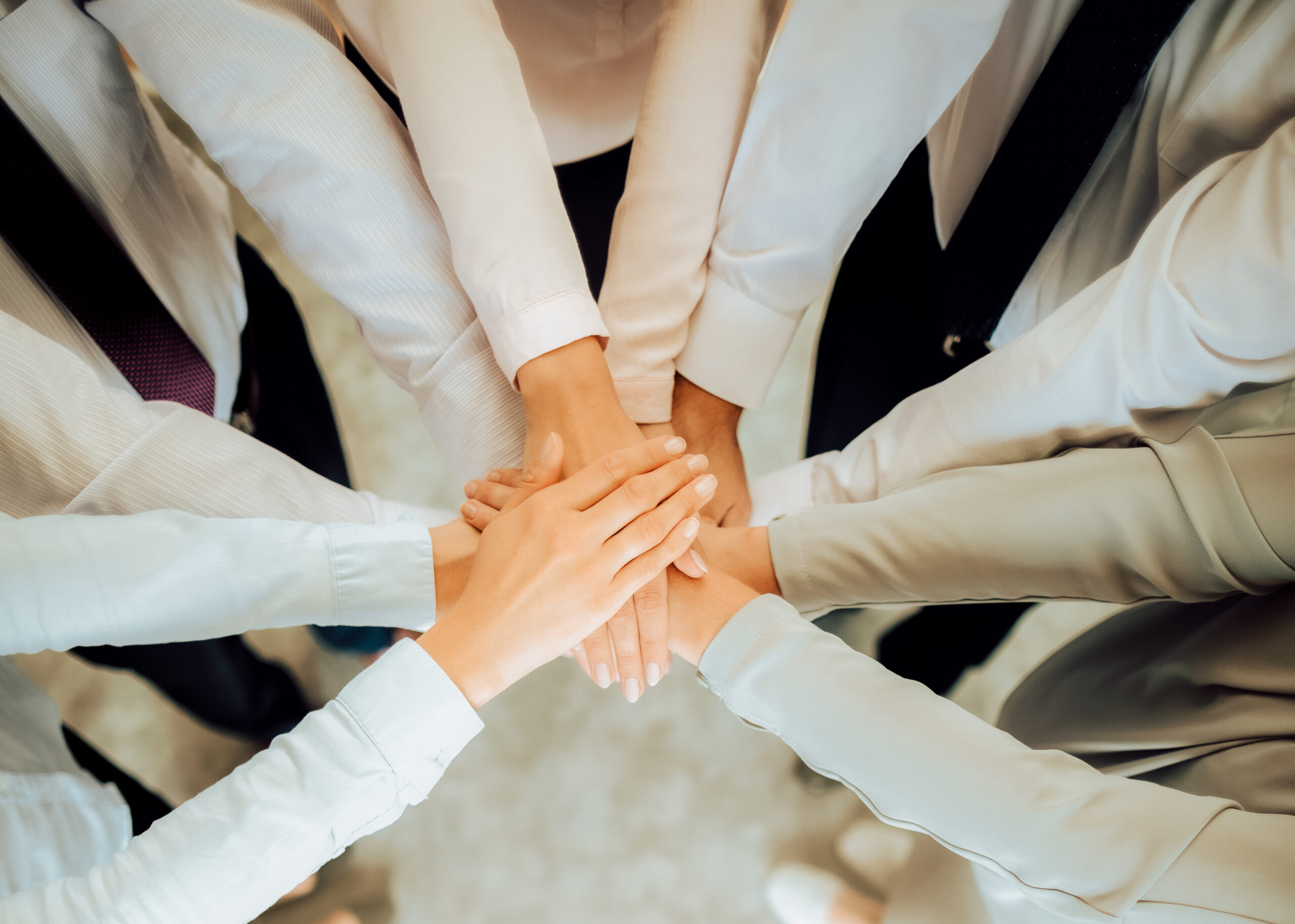 Close up top view of young business people putting their hands together Close up top view of young business people putting their hands together